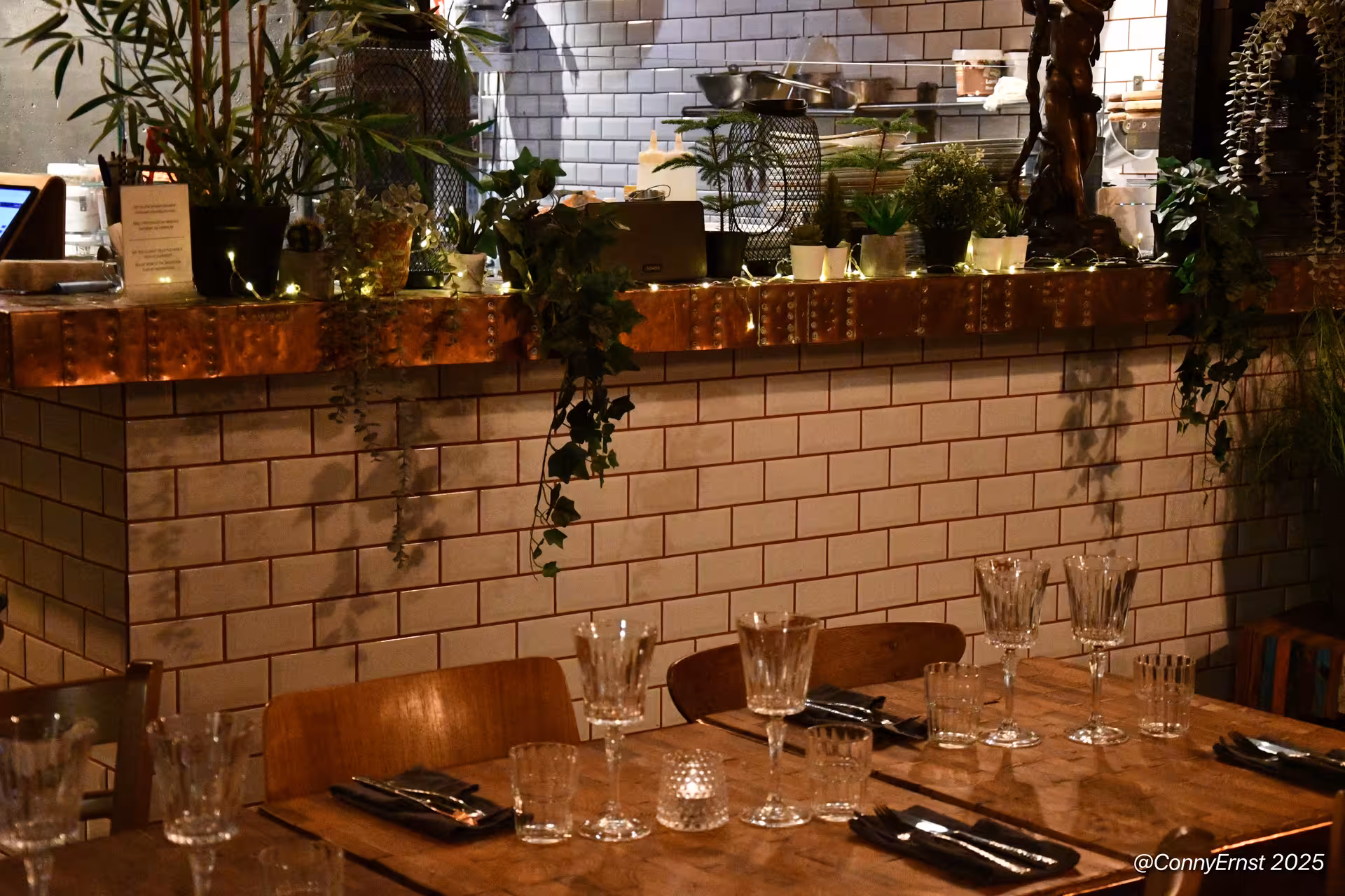 Cozy Icelandic restaurant interior with rustic wooden tables, crystal glassware, ivy decor, and warm candlelight