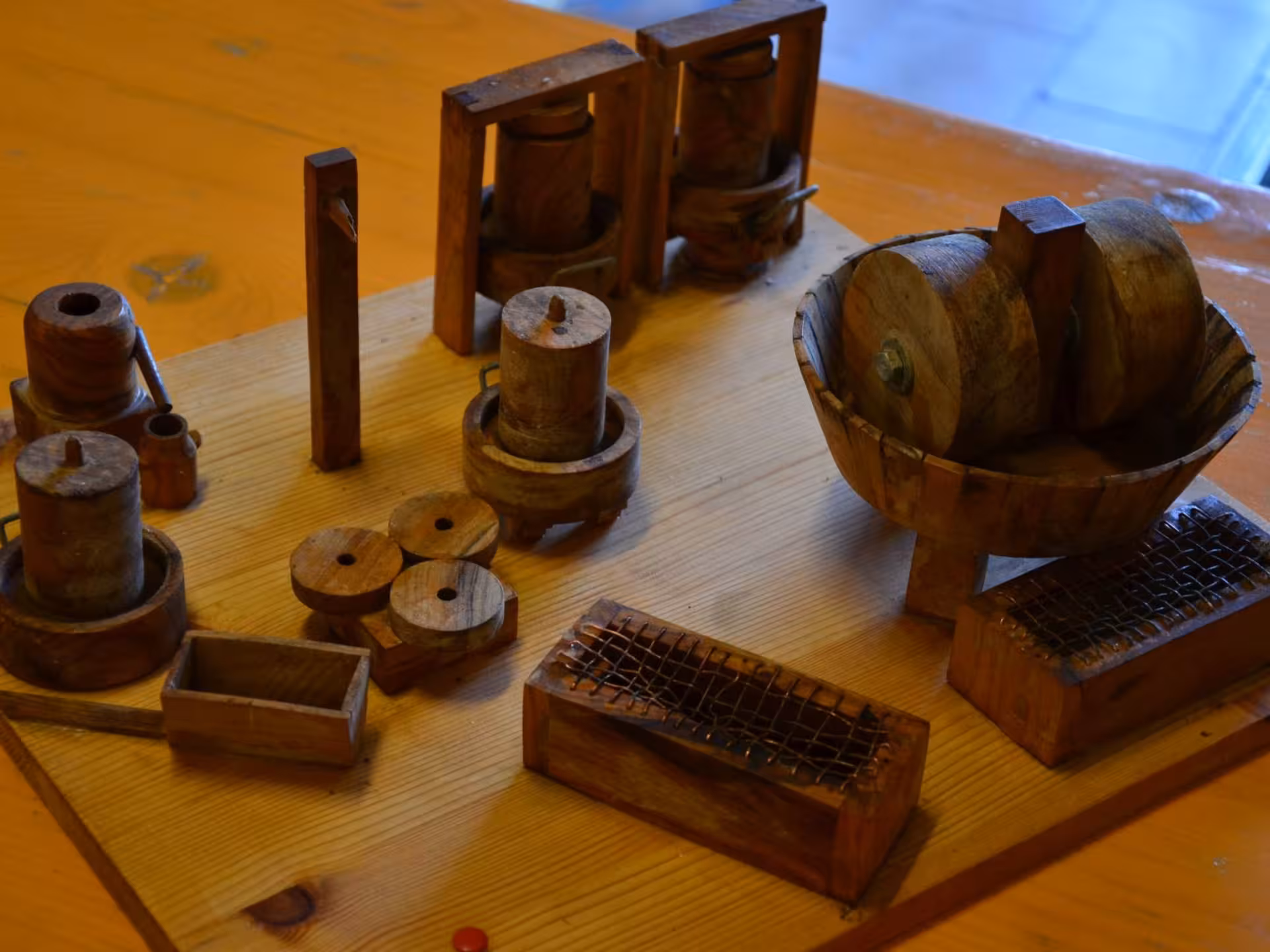 Intricate wooden models of traditional olive oil processing equipment displayed on a tabletop in Chianciano.