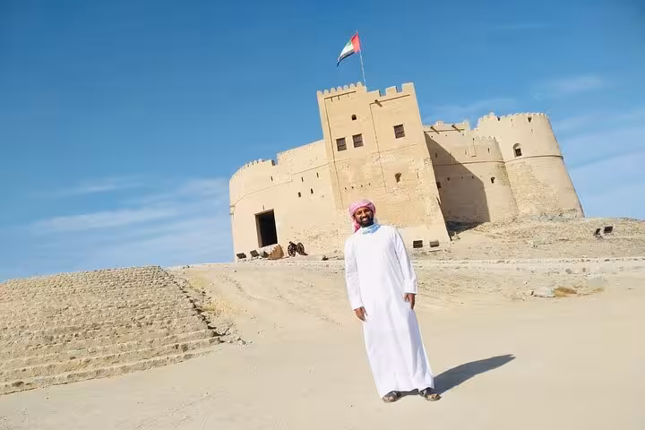 Traditional UAE fort with flag in desert, key stop on Emirates tours for history, culture and attractions