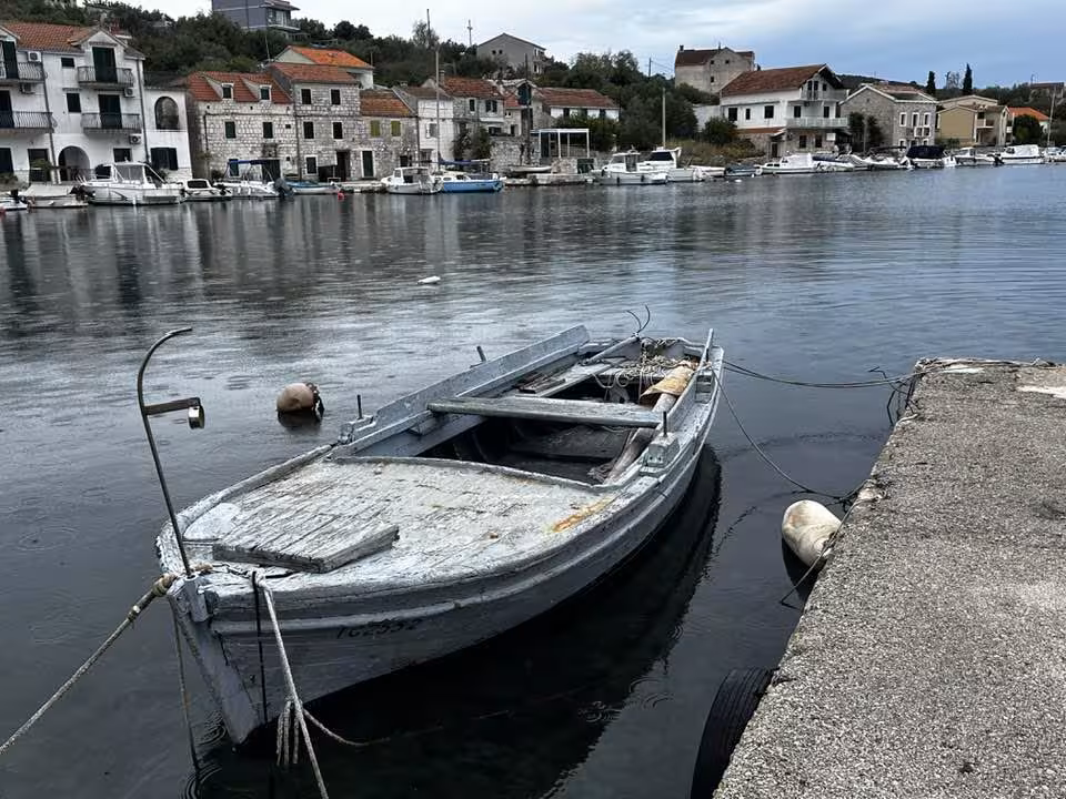 Old wooden fishing boat moored at a stone quay in a small Croatian coastal village harbor