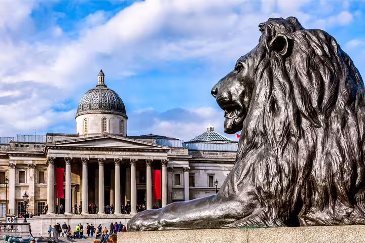 Statue of a lion in Trafalgar Square with the National Gallery in the background, featured on a private London city tour.