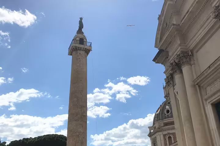 Trajan's Column and classical Roman building facade against blue sky in ancient Rome
