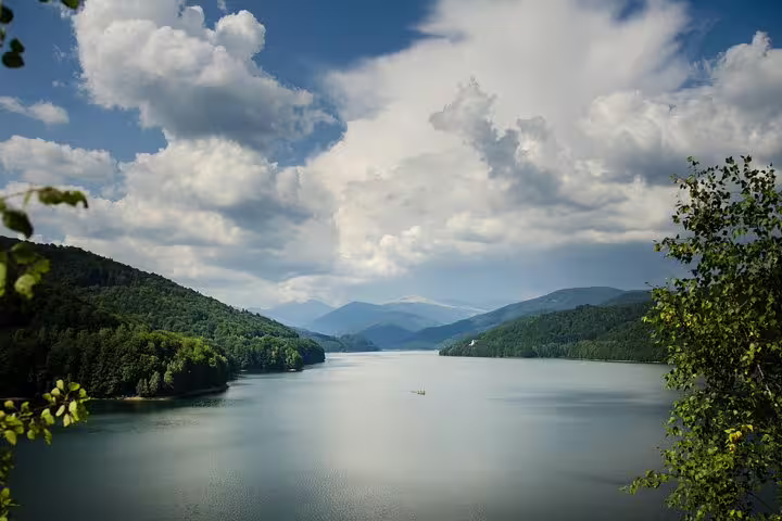 Scenic lake surrounded by forested mountains along Transfagarasan Road, Romania