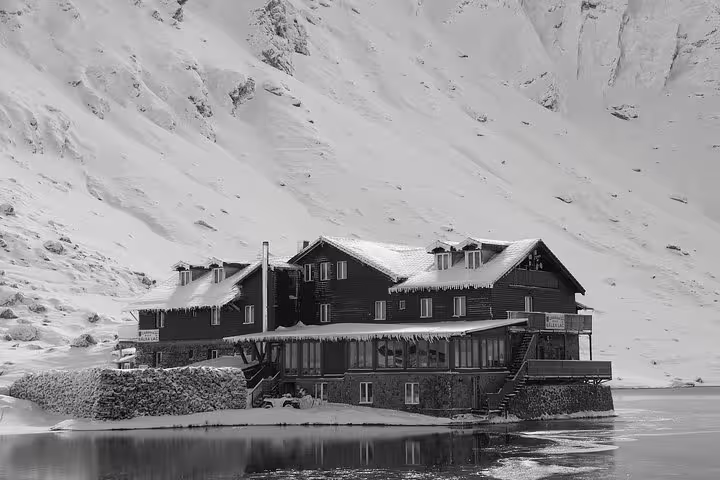 Snow-covered mountain lodge on Transfagarasan Road surrounded by steep snowy slopes in winter