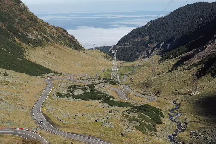 Winding Transfagarasan Road serpentines through mountain valley above clouds in Romania