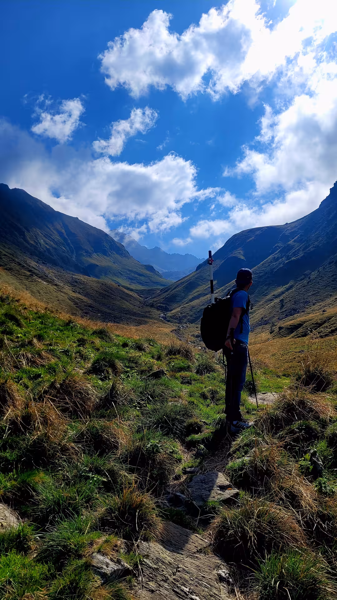 Hiker with trekking pole and backpack gazing at a scenic mountain valley in Transylvania