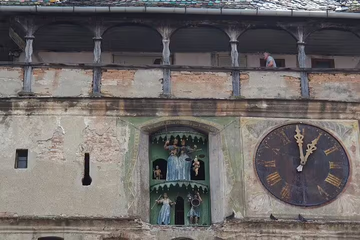 Medieval clock tower with ornate figurines and Roman numeral clock face in Transylvania