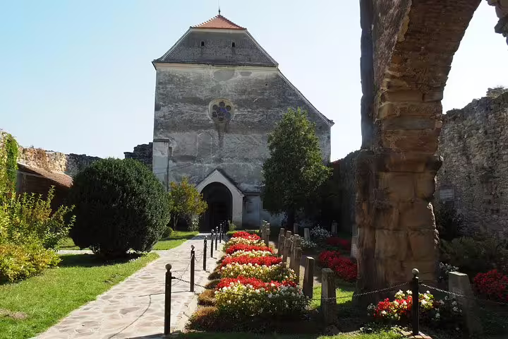 Medieval church with rose window surrounded by colorful flower gardens in Transylvania, Romania