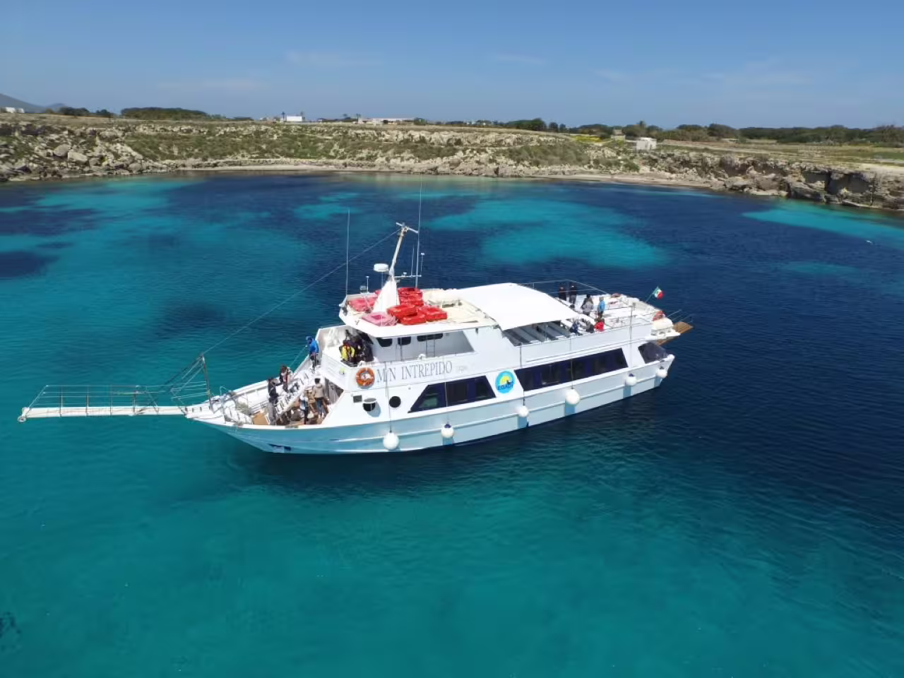 Boat anchored in crystal-clear bay on Trapani mini-cruise to Favignana and Levanzo, Egadi Islands snorkeling