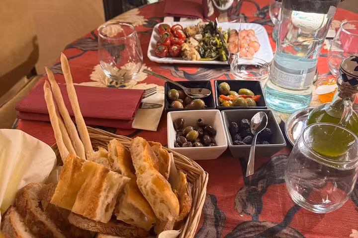 Basket of fresh Italian bread, olives and antipasti on a colorful table during a Trastevere food tour in Rome