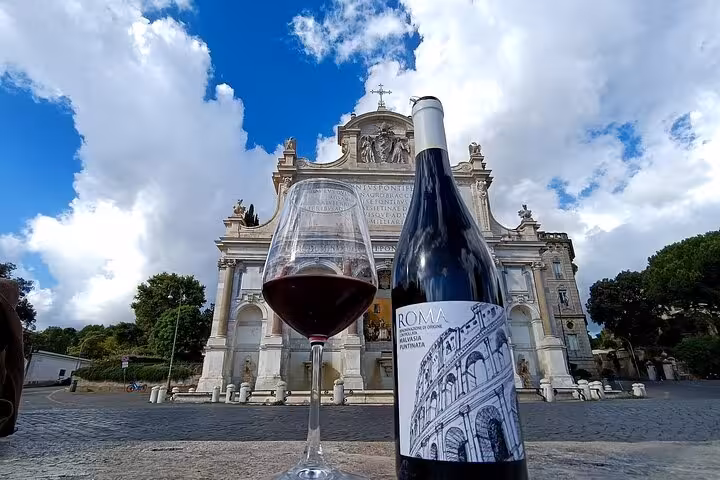 Glass of red wine and bottle of Lazio vintage in front of historic Roman church on Trastevere gourmet wine tour
