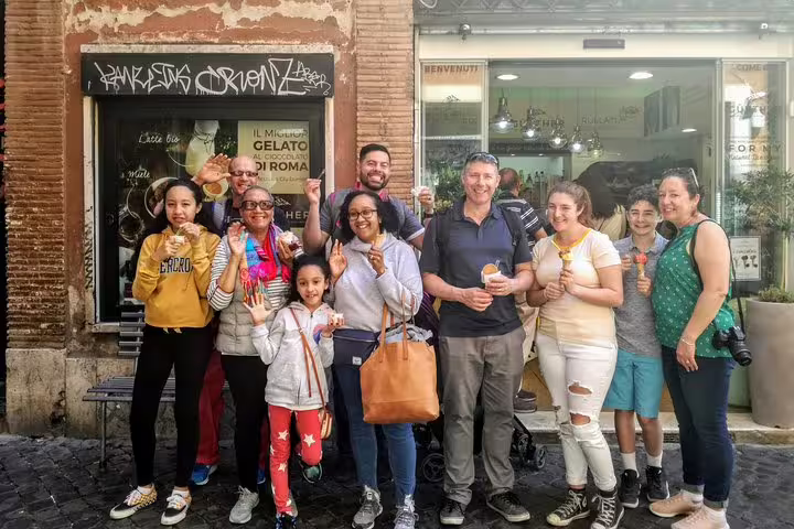 Happy tour group holding gelato cones outside a famous Trastevere gelateria on a Rome street food walking tour.