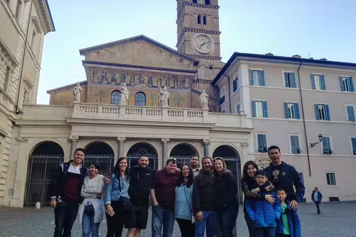 Tour group posing in front of the historic Santa Maria in Trastevere basilica during a Rome sightseeing walking tour.