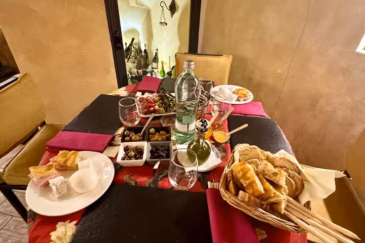Cozy Trastevere wine tasting table set with Italian antipasti, olives, focaccia and local cheeses in a rustic Roman cellar