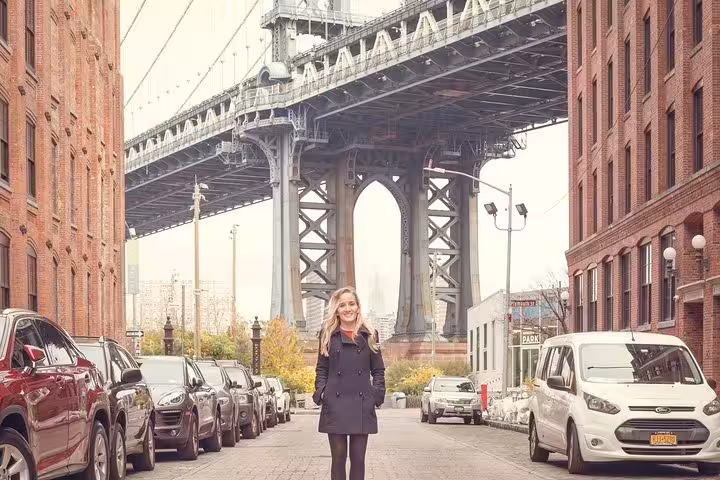 Traveler posing on Brooklyn street under Manhattan Bridge in DUMBO, NYC on a personal photography tour
