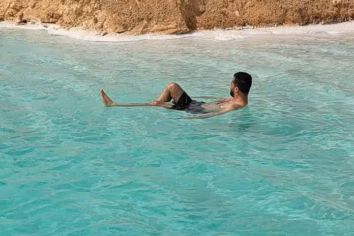 Traveler floating in Siwa Oasis salt lake, Egypt, on a private 3-day Sahara safari desert tour
