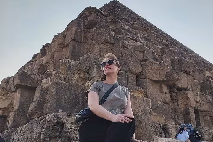 Traveler posing by ancient stone blocks at Giza Pyramid during a private Cairo day trip to Pyramids and GEM