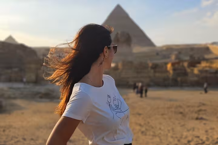 Traveler at Giza Pyramids during Cairo day tour, sunset view from desert plateau near Great Sphinx