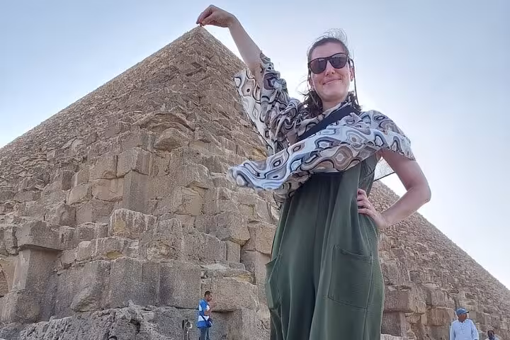 Traveler posing by the Great Pyramid of Giza on an all-inclusive guided tour of Giza, Saqqara and Memphis