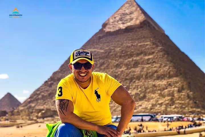 Smiling traveler posing by the Great Pyramid of Giza, classic photo stop on a horse carriage half-day tour