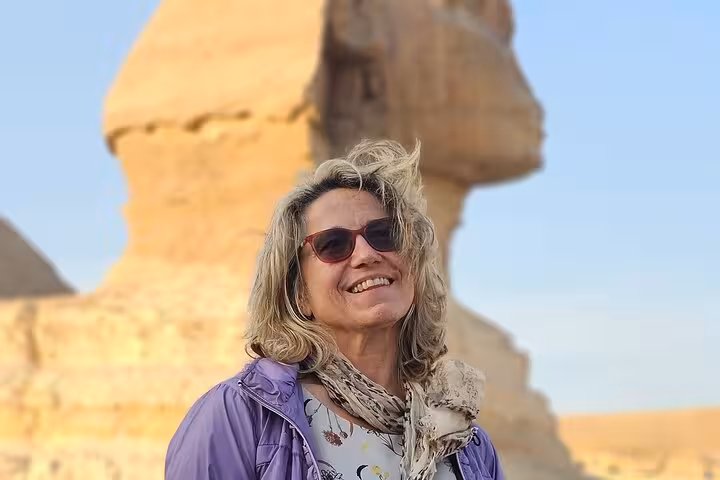 Smiling traveler at the Great Sphinx of Giza on a fly to Cairo tour to explore pyramids and museums
