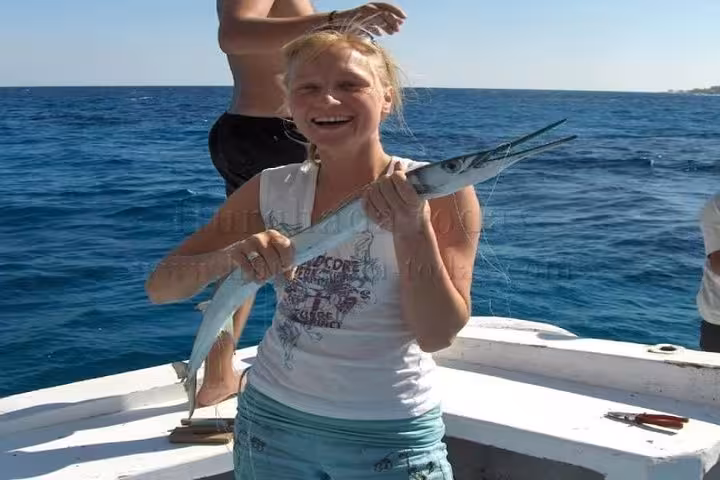Traveler holding a fish on a Red Sea boat in Hurghada, optional activity on Luxor snorkeling day trip