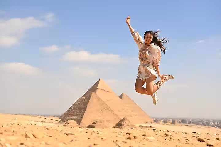Traveler jumping near the Giza Pyramids on a Cairo day tour by plane from Marsa Alam, Egypt