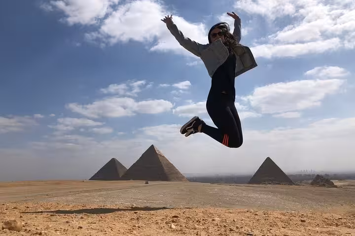 Traveler jumping with Giza Pyramids backdrop on a private Giza pyramids and Sphinx tour with lunch