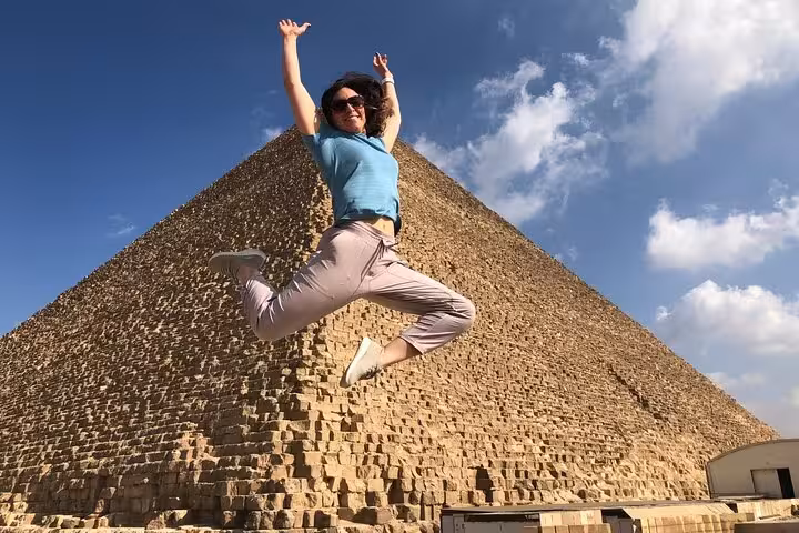 Traveler jumping in front of the Great Pyramid of Giza on a private tour with ATV, camel ride and cruise