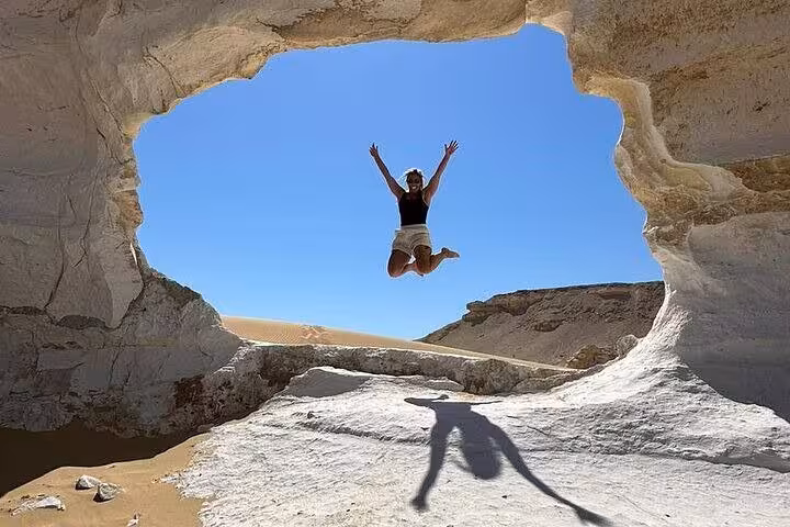 Traveler jumping inside a natural rock arch in Egypt’s White Desert, highlight of a 2-day private safari tour