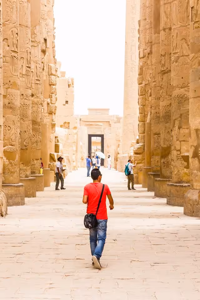 Traveler walking between towering Karnak Temple columns in Luxor, Egypt Explorer felucca and Red Sea trip