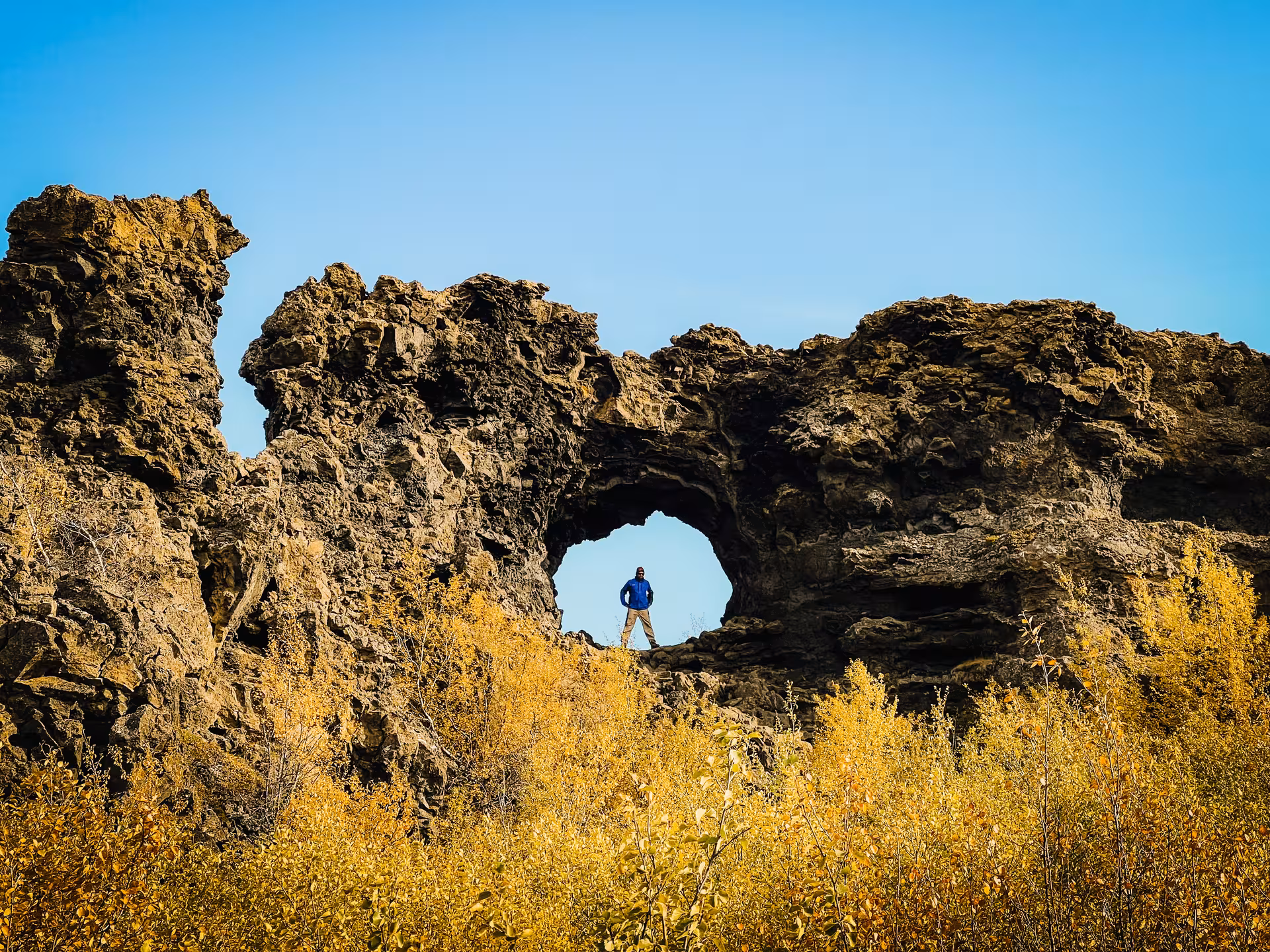 Traveler standing in a lava rock arch near Lake Mývatn, a stop on the private Goðafoss and Dettifoss adventure
