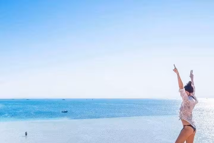 Traveler celebrating on a sandy sandbank at Lovely Island Hurghada, Red Sea day trip and swim stop