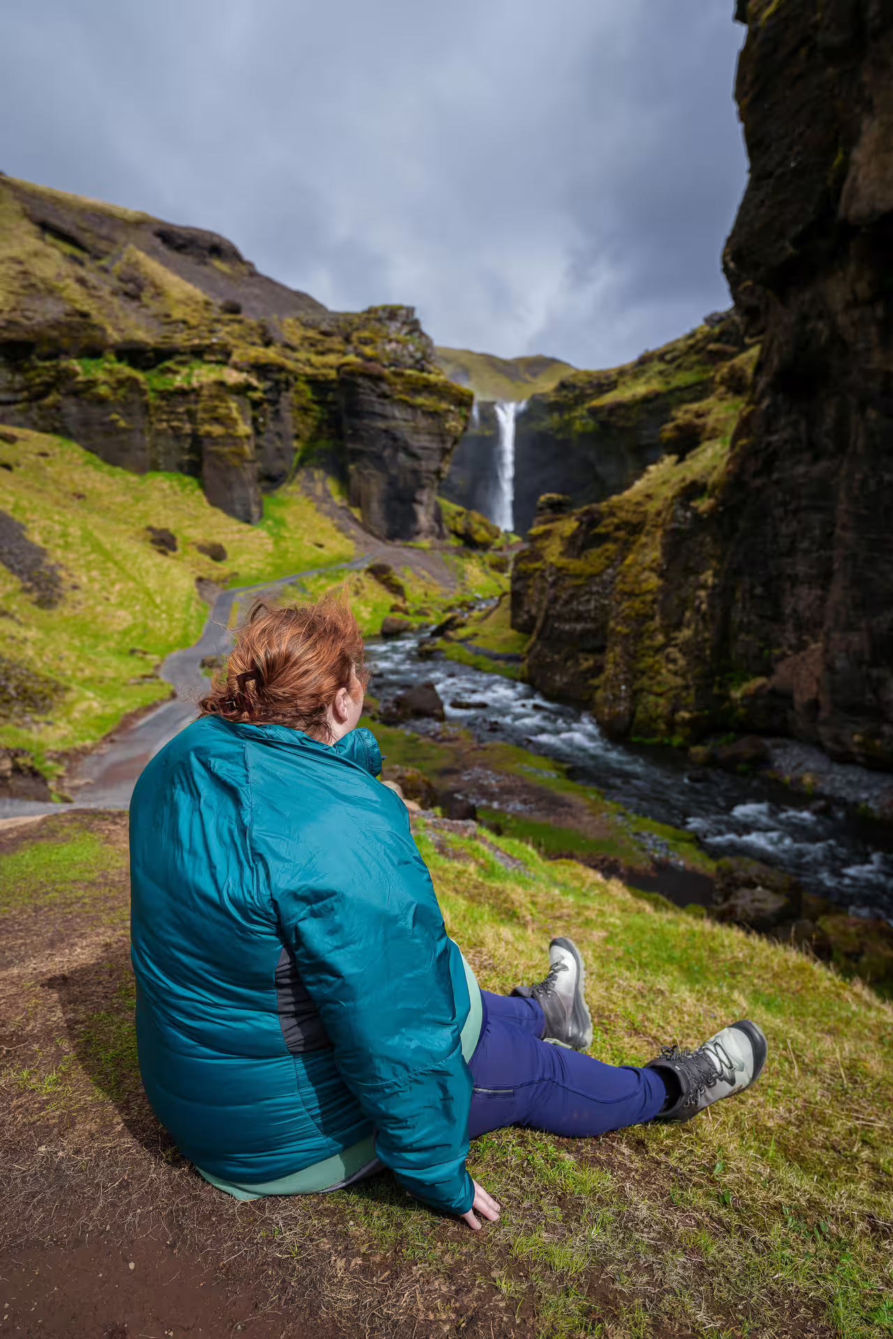 Traveler sitting on mossy cliffs admiring a stunning Iceland waterfall canyon on a Southeast Iceland Viking Journey tour