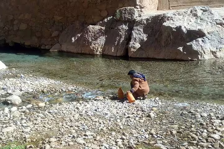 Traveler rests by a clear river oasis stop on 3-day private desert tour from Marrakech to Merzouga