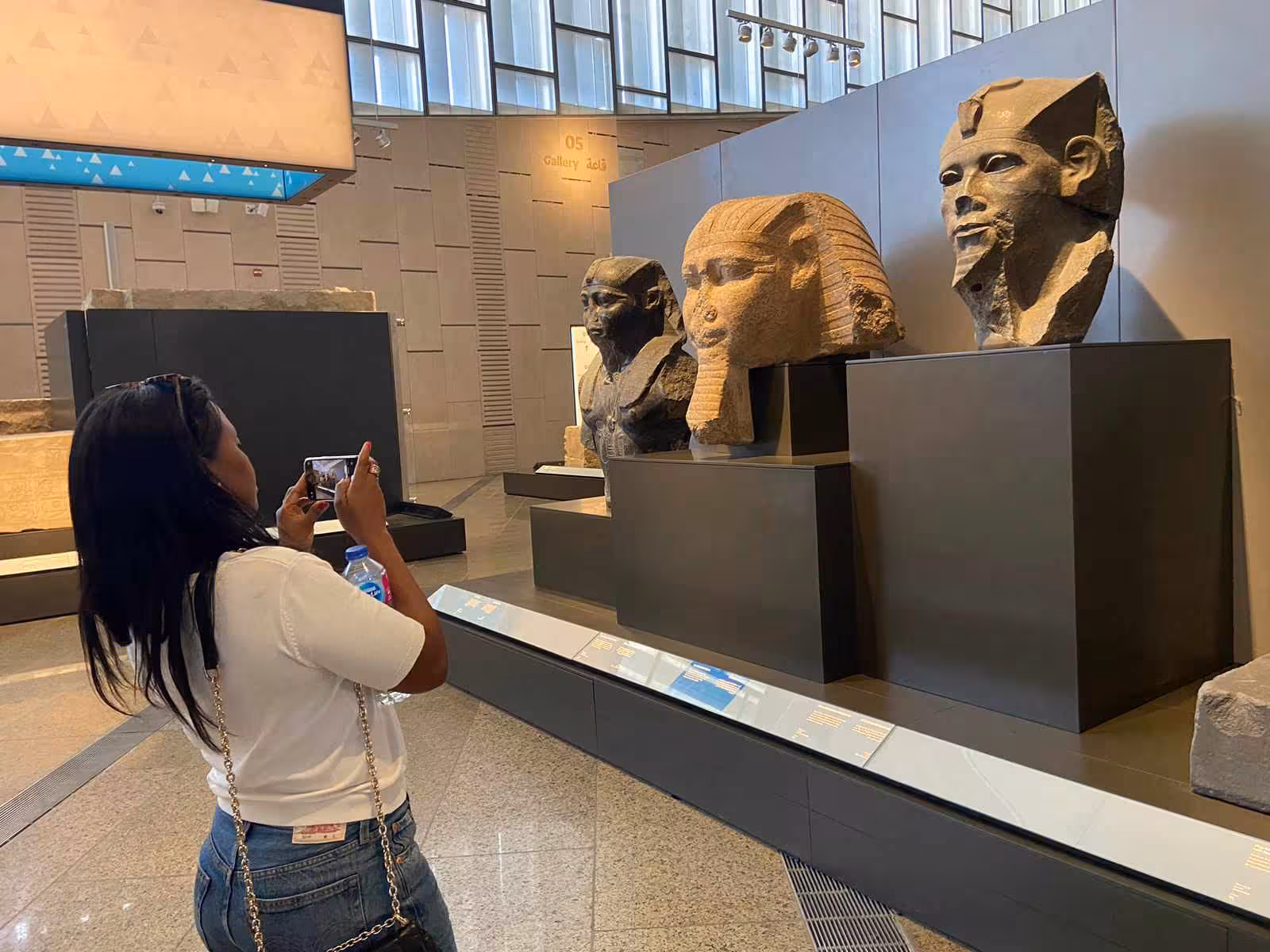 Traveler photographing colossal pharaoh heads inside the Grand Egyptian Museum on Giza Pyramids and lunch tour
