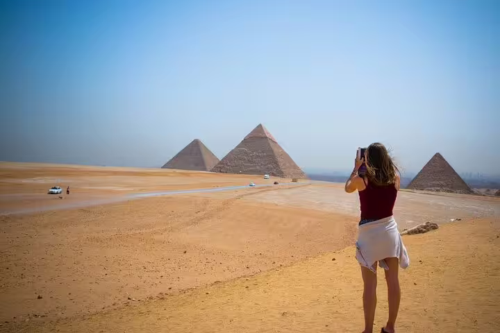 Traveler photographing the Pyramids of Giza plateau, perfect for a Cairo day tour with Egyptian Museum visit and Nile dinner cruise