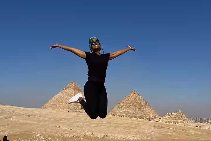 Traveler jumping with arms wide at the Pyramids of Giza on a Cairo private tour with Egyptian lunch