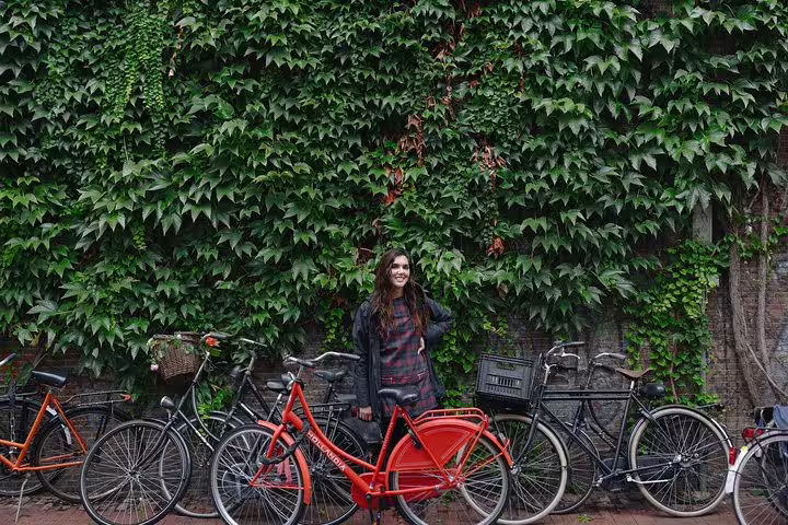 Traveler posing with red bike by ivy wall in Amsterdam, captured on a personal travel photographer tour