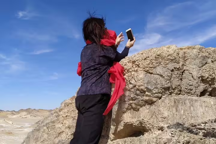 Traveler taking photos on rocky ridge in Egypt White Desert, scenic moment on 3 days 2 nights Bahariya Oasis tour
