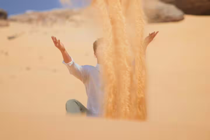 Traveler tossing sand in Egypt’s White Desert dunes during private 4-day Bahariya Oasis and White Desert tour