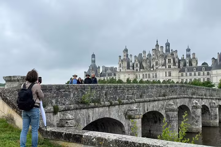 Travelers on bridge facing Château de Chambord, highlight of Incredible Loire castles tour with lunch and wine tasting