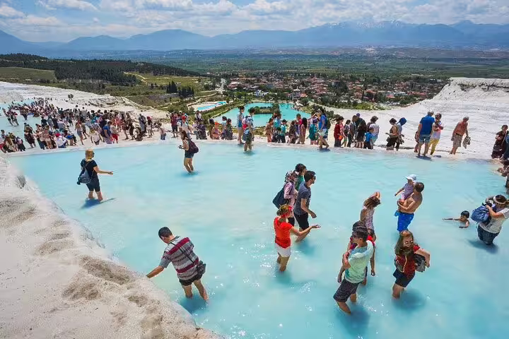 Travelers wading in Pamukkale thermal terrace pool with white travertines on a 3-day Ephesus tour