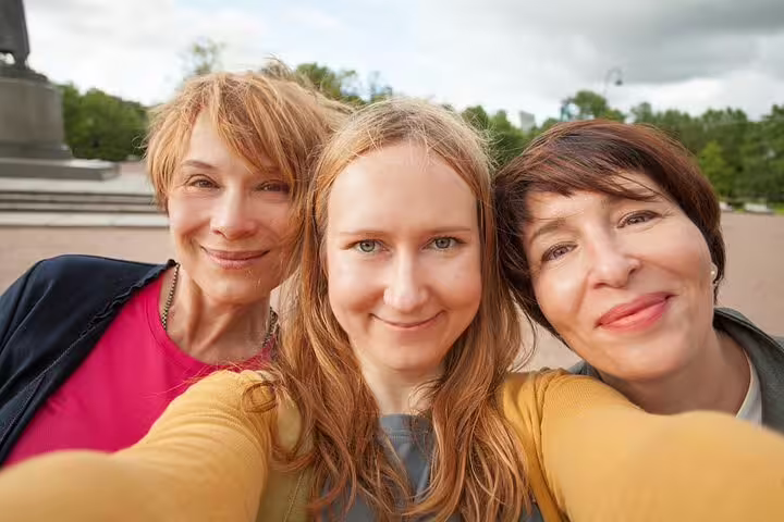 Three travelers smiling for a selfie while playing a Pisa e-scavenger hunt, a fun self-guided city exploration tour