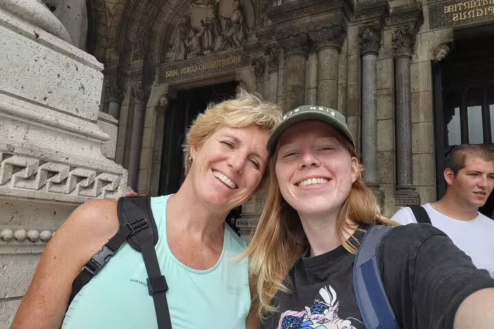 Happy travelers selfie at Sacré-Cœur Basilica entrance during Paris Montmartre scavenger hunt self-guided tour
