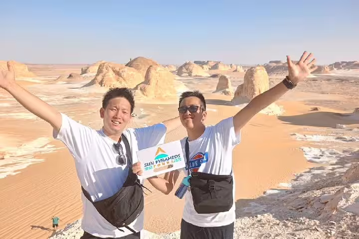 Happy travelers with arms raised overlooking White Desert rock pillars on a private 4-day Bahariya Oasis tour