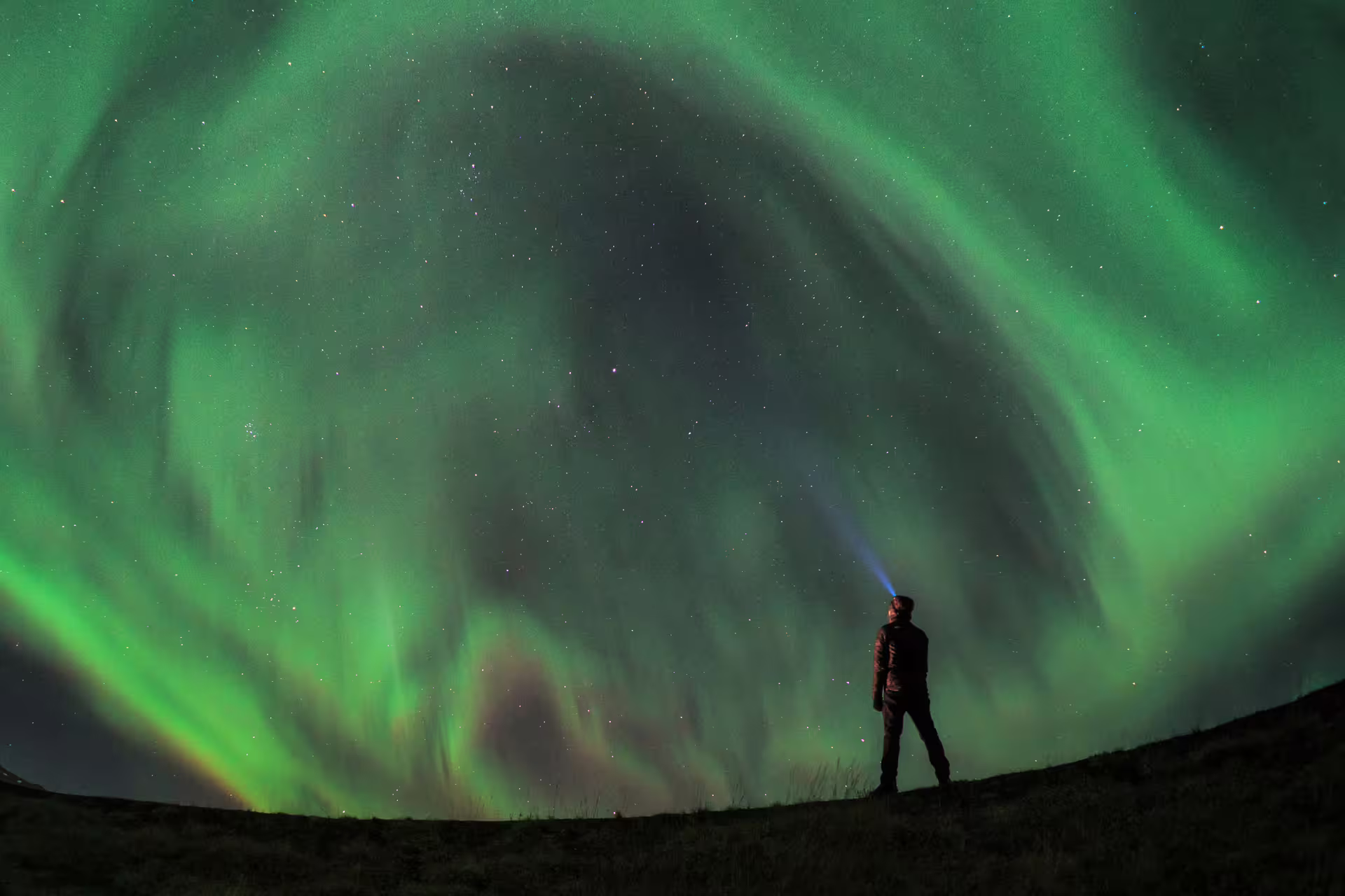 A traveller taking a selfie with a solar storm shown in the background 