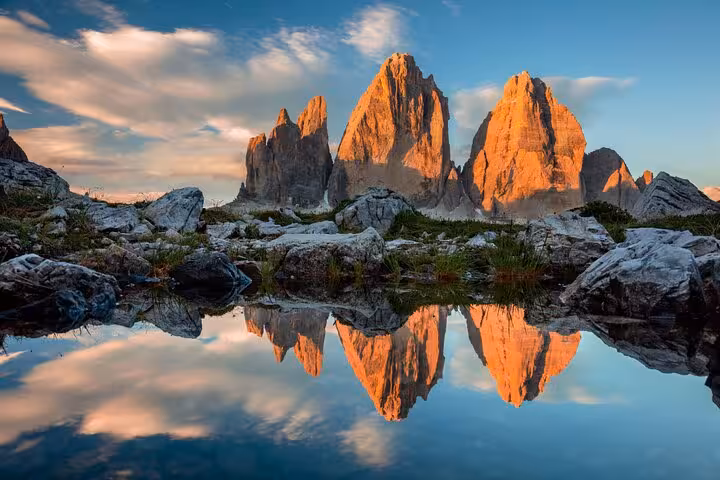 Scenic view of Tre Cime di Lavaredo reflecting in a tranquil lake during sunset, en route from Venice to Cortina d'Ampezzo.