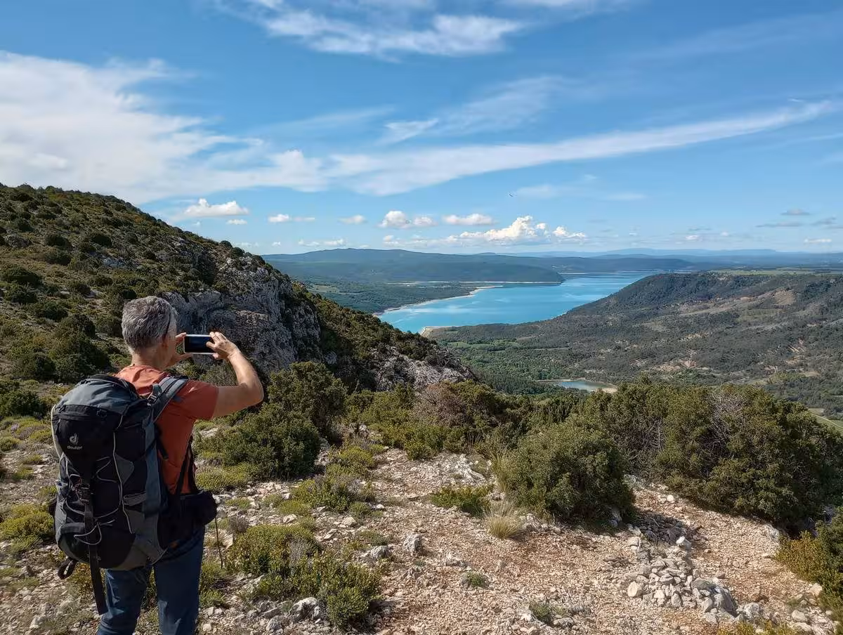 Hiker photographing turquoise Lake Sainte-Croix viewpoint on 6-day Verdon Gorge Grand Canyon hiking tour, France