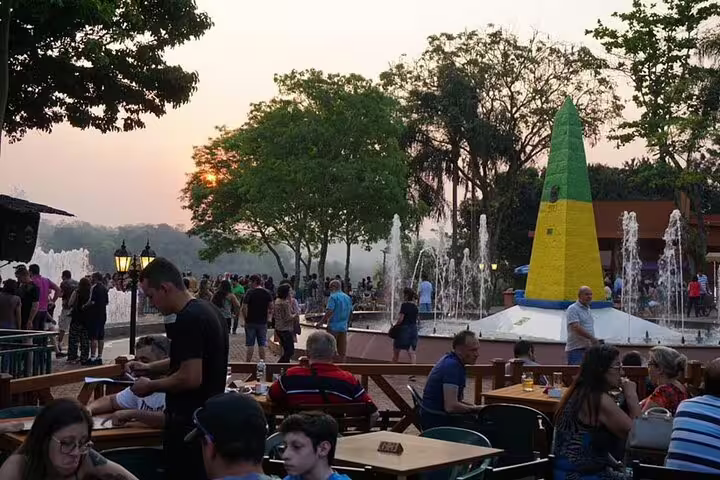 Lively scene at Tres Fronteiras with visitors enjoying the landmark and fountains during a serene sunset.